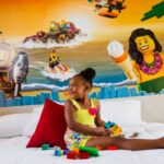 LEGOLAND Florida: A young girl sitting on a bed with Legoland Florida legos on it.