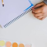LEGOLAND Florida: A person is writing on a notebook next to paints and watercolors.