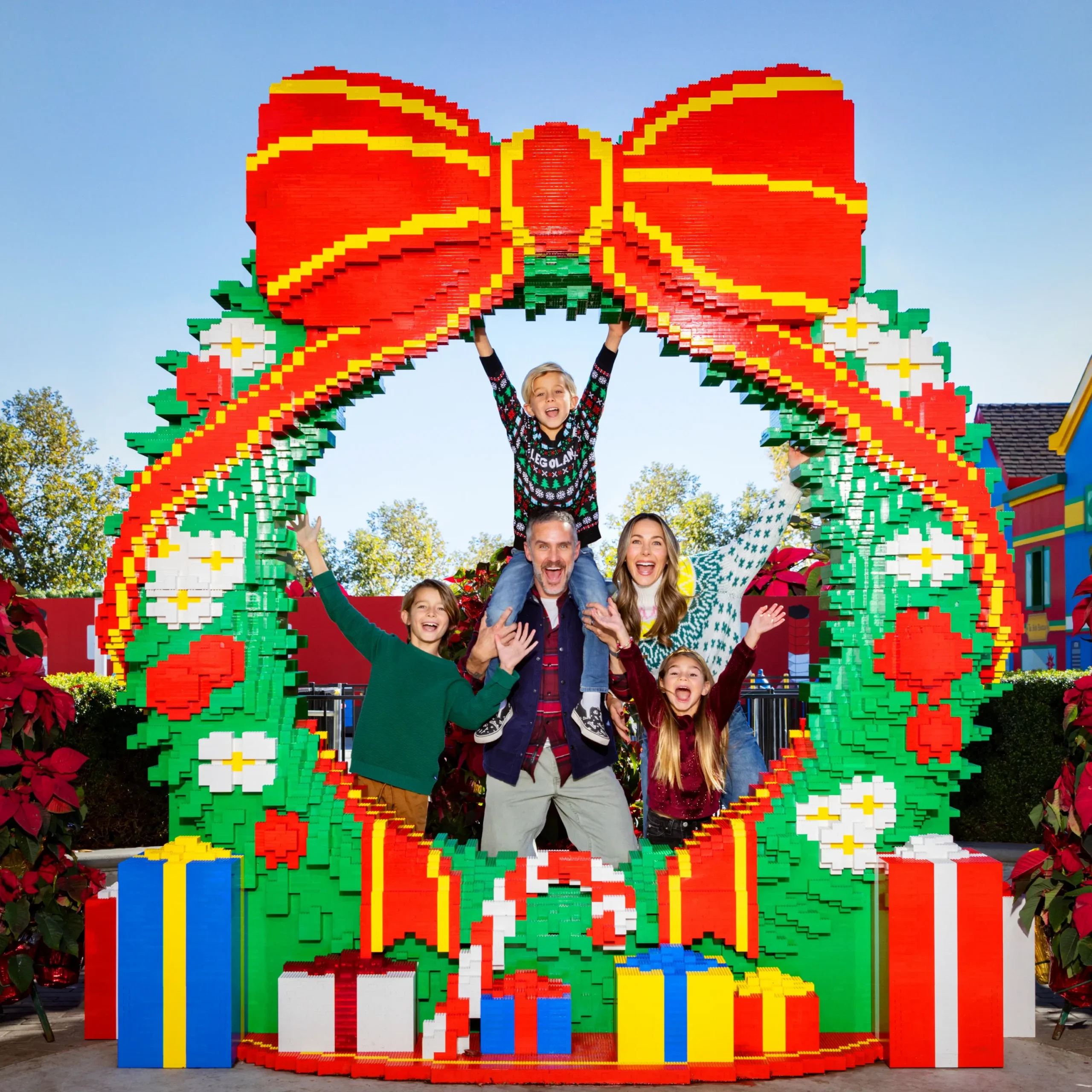 LEGOLAND Florida Christmas Bricktacular 2026: LEGO Santa Takes to the Sky 10 Family posing inside the giant LEGO holiday wreath at LEGOLAND Florida